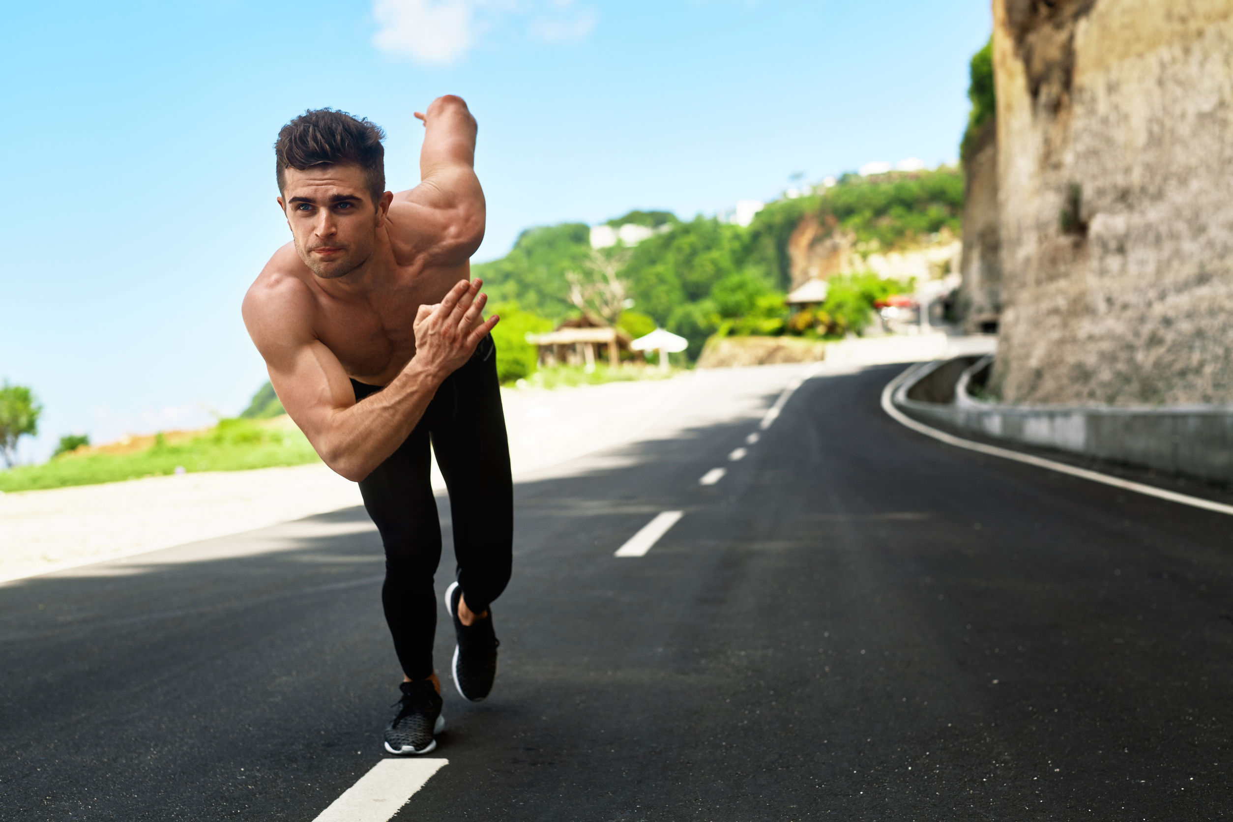 57159660 - athletics. athletic man with fit muscular body in starting position for running on road. handsome runner ready to start sprint race. fitness model training outdoors in summer. sports workout concept